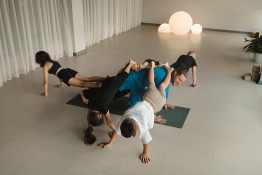 A team of children and a coach do an unusual pose at an indoor yoga workout.