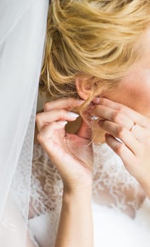 beautiful gorgeous bride putting on luxury earrings.