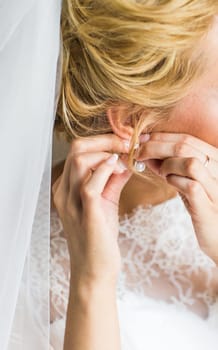 beautiful gorgeous bride putting on luxury earrings.