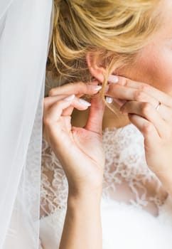 beautiful gorgeous bride putting on luxury earrings.