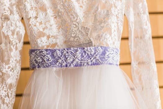 The perfect wedding dress with a full skirt on a hanger in the room of the bride