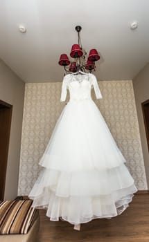 The perfect wedding dress with a full skirt on a hanger in the room of the bride