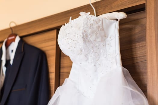 The perfect wedding dress with a full skirt on a hanger in the room of the bride