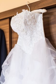 The perfect wedding dress with a full skirt on a hanger in the room of the bride