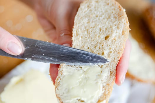 Close-up of woman's hands spreading butter on a slice of bread. Quick food for hiking or if you don't have time to make food. High quality photo