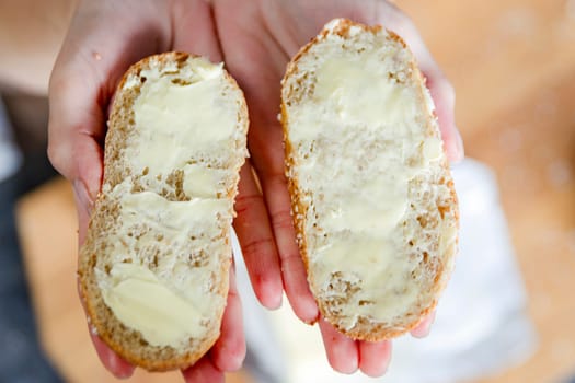 Women's hands hold two slices of bread spread with butter close-up. Quick food for hiking or if you don't have time to make food. High quality photo
