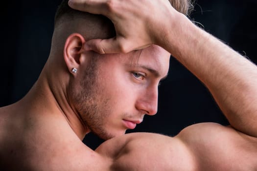 A shirtless man holding his head in his hands