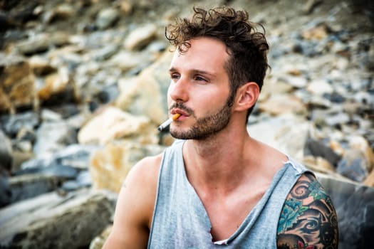A handsome man with a cigarette in his mouth. Photo of a man smoking a cigarette outdoor