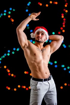 A shirtless man wearing a santa claus hat