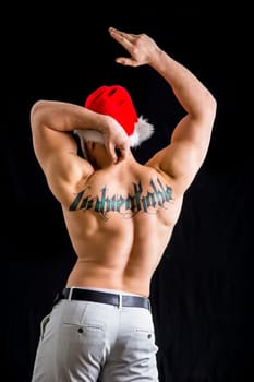 A shirtless man with a santa hat on