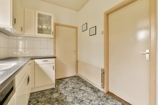 an empty kitchen with white cabinets and marble counter tops on the floor in front of the door to the room