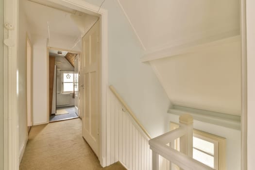 a long hallway with white trim on the walls, and carpeted stairs leading up to an open door that leads to another room