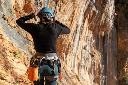 A young girl is engaged in active sports, rock climbing and mountaineering. A woman looks at a beautiful red rock and takes magnesia in her hand, getting ready for training and climbing.
