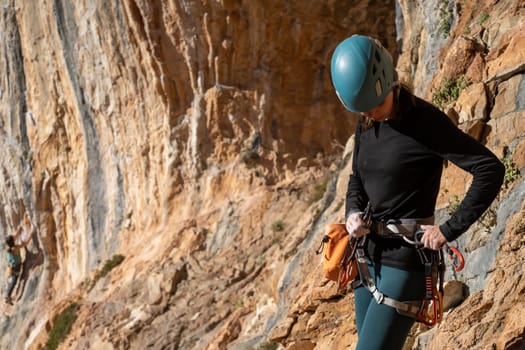 A young girl is engaged in active sports, rock climbing and mountaineering. A woman looks at a beautiful red rock and takes magnesia in her hand, getting ready for training and climbing.