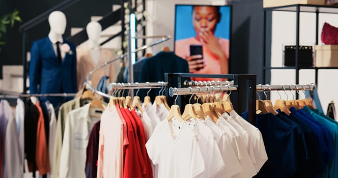 Empty clothing store in shopping mall, new fashion collection on shelf. Fashionable clothes on hangers and racks, modern boutique filled with merchandise and accessories at sale for customers