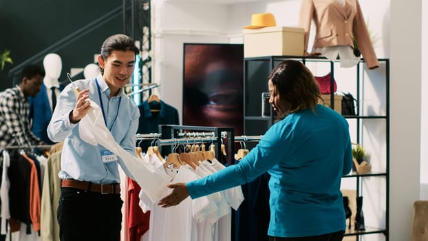 African american customer shopping for casual wear, discussing outfit material with boutique manager. Shopaholic woman buying fashionable clothes in clothing store. Fashion concept