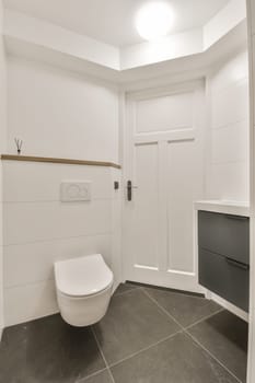 a white toilet in a small bathroom with black and white tiles on the floor, there is an open door