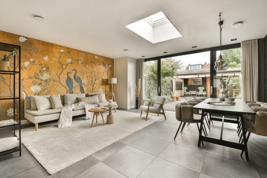 a living room with orange and white wallpapers on the walls, couches, chairs, coffee table and windows