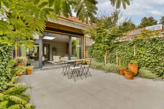 an outdoor patio with plants and pots on the concrete floor, surrounded by lush green trees in the background