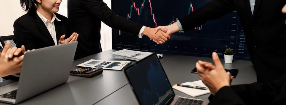 Stock investors celebrate successful profit from selling stock and shaking hand with each other, market analysis and strategic decision-making led to successful stock trading exchange. Trailblazing