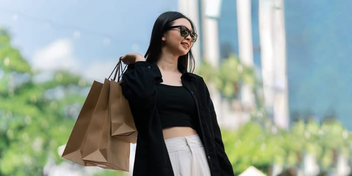 Young asian woman in shopping. Fashion woman in black with shopping bag walking out store after shopping. Black friday.