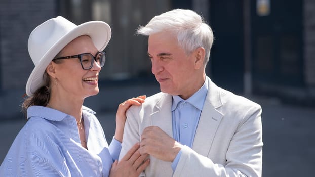 An elderly couple in love walks through the city. Portrait of a stylish gray-haired man and woman