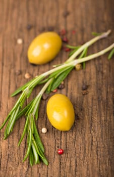 Close up green olives, rosemary on a wooden background