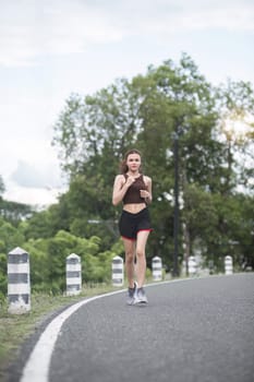 Young sporty woman jogging in the green park in the evening.