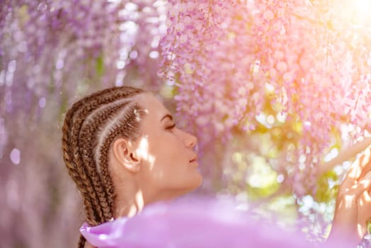 Woman wisteria lilac dress. Thoughtful happy mature woman in purple dress surrounded by chinese wisteria.