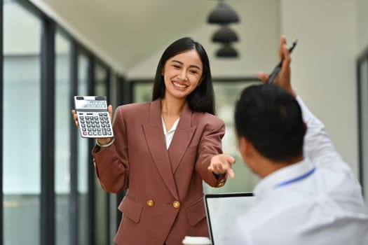 Smiling asian female employee asking question, interacting with team at corporate meeting.