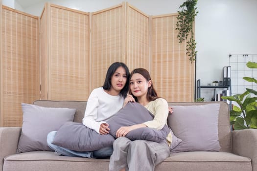 LGBT, Two beautiful scared girls watching horror movie at living room..