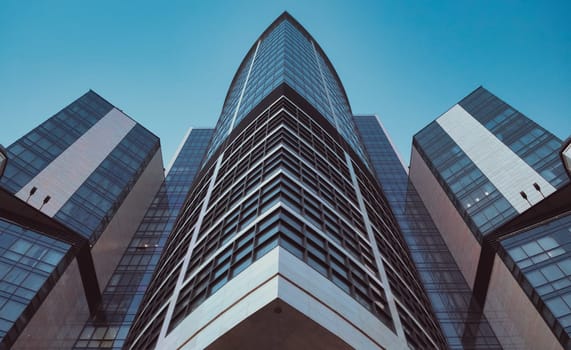 Bottom view of modern skyscrapers in business district against blue sky. Looking up at business buildings in downtown. Rising sun on the horizon. download photo