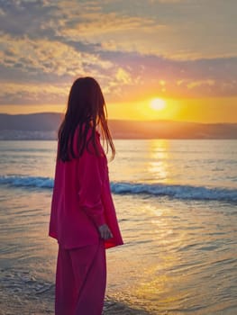 Aesthetic young woman rear view watching the sunrise above the hills at the sea. Beautiful dawn scene, summer holiday background