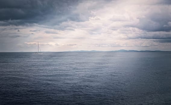 Panoramic seascape with a sailboat on the horizon