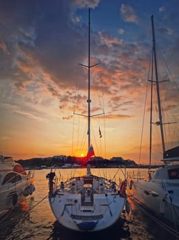 Sunset scene at the harbor as seen through the yachts moored at the deck in the ancient town of Nessebar, Burgas, Bulgaria