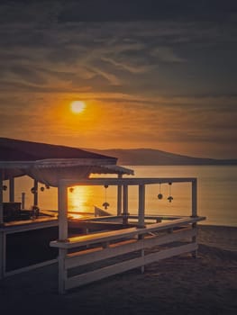 Early morning seaside next to beach bar with a beautiful view to the sunrise over the sea. Vacation and relax concept