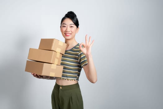Portrait of young Asian business woman with boxes showing OK sign