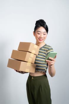  Smiling young woman holding cardboard box and talking on cellphone looking away at blank copy space