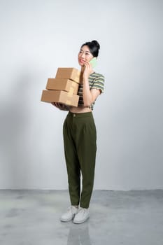 happy young woman calling on her smartphone while standing with a cardboard box isolated
