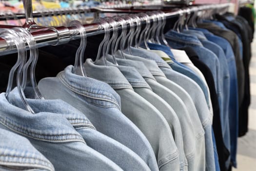 Denim jackets and shirts hanging in a row in a store