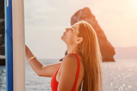 Close up shot of beautiful young caucasian woman with black hair and freckles looking at camera and smiling. Cute woman portrait in a pink bikini posing on a volcanic rock high above the sea