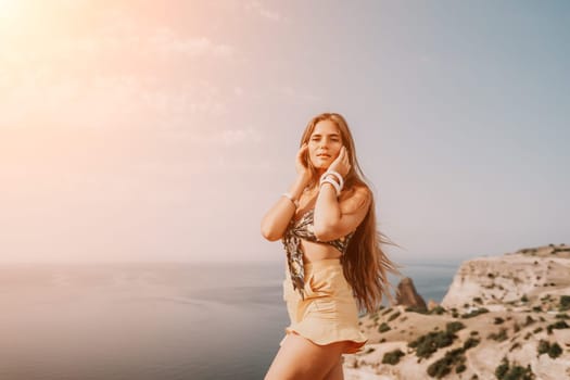 Woman travel sea. Happy tourist taking picture outdoors for memories. Woman traveler looks at the edge of the cliff on the sea bay of mountains, sharing travel adventure journey.