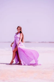 Woman pink salt lake. Against the backdrop of a pink salt lake, a woman in a long pink dress takes a leisurely stroll along the white, salty shore, capturing a wanderlust moment