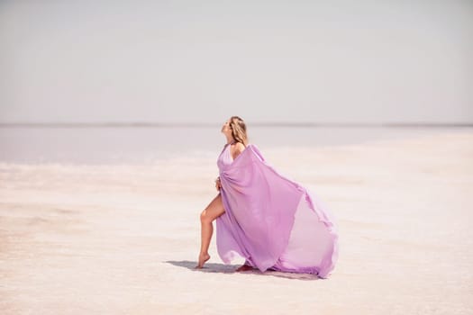 Woman pink salt lake. Against the backdrop of a pink salt lake, a woman in a long pink dress takes a leisurely stroll along the white, salty shore, capturing a wanderlust moment