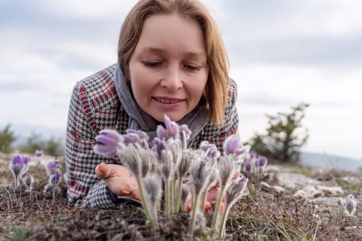 Dream grass woman spring flower. Woman lies on the ground and hugs flowers pasqueflower or Pulsatilla Grandis flowers.