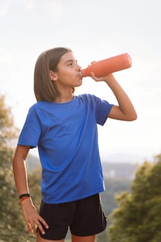 girl drinking water during her training, concept of sport in nature for children and healthy lifestyle