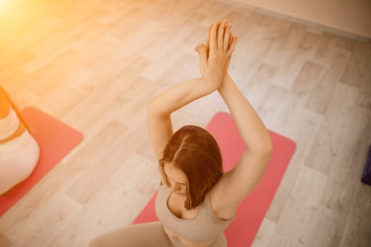 Girl does yoga. Young woman practices asanas on a beige one-ton background