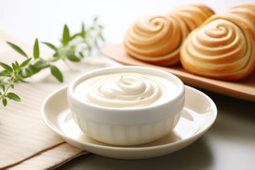 A bowl of whipped cream against a background of blurry freshly baked scones.