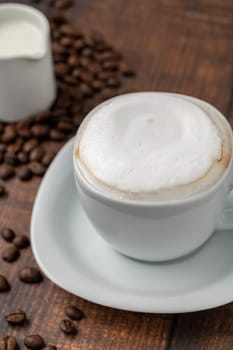Cappuccino coffee in a white porcelain cup on a wooden table