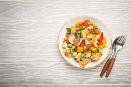 Traditional Levant dish Fattoush salad, Arab cuisine, with pita bread croutons, vegetables, herbs. Healthy Middle Eastern vegetarian salad, rustic wooden white background top view, space for text.